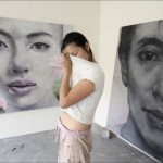 Chong, standing between two of her works, wiping off perspiration with her t-shirt.