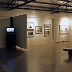 A guest contemplating the exhibition. On the left is a slideshow on the making of WORKING, documented by the participating artists.