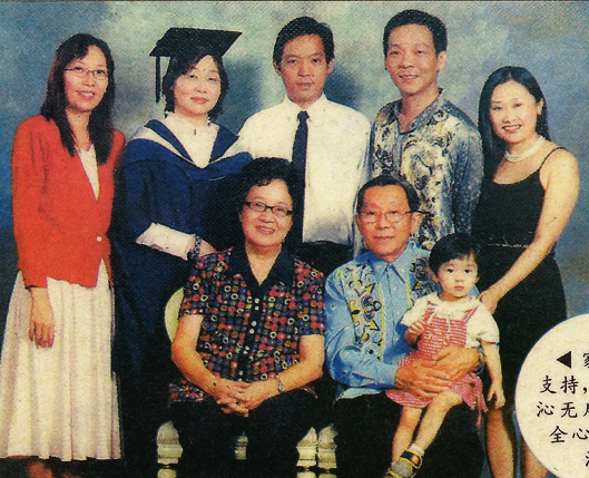 With her family. Her parents are seated